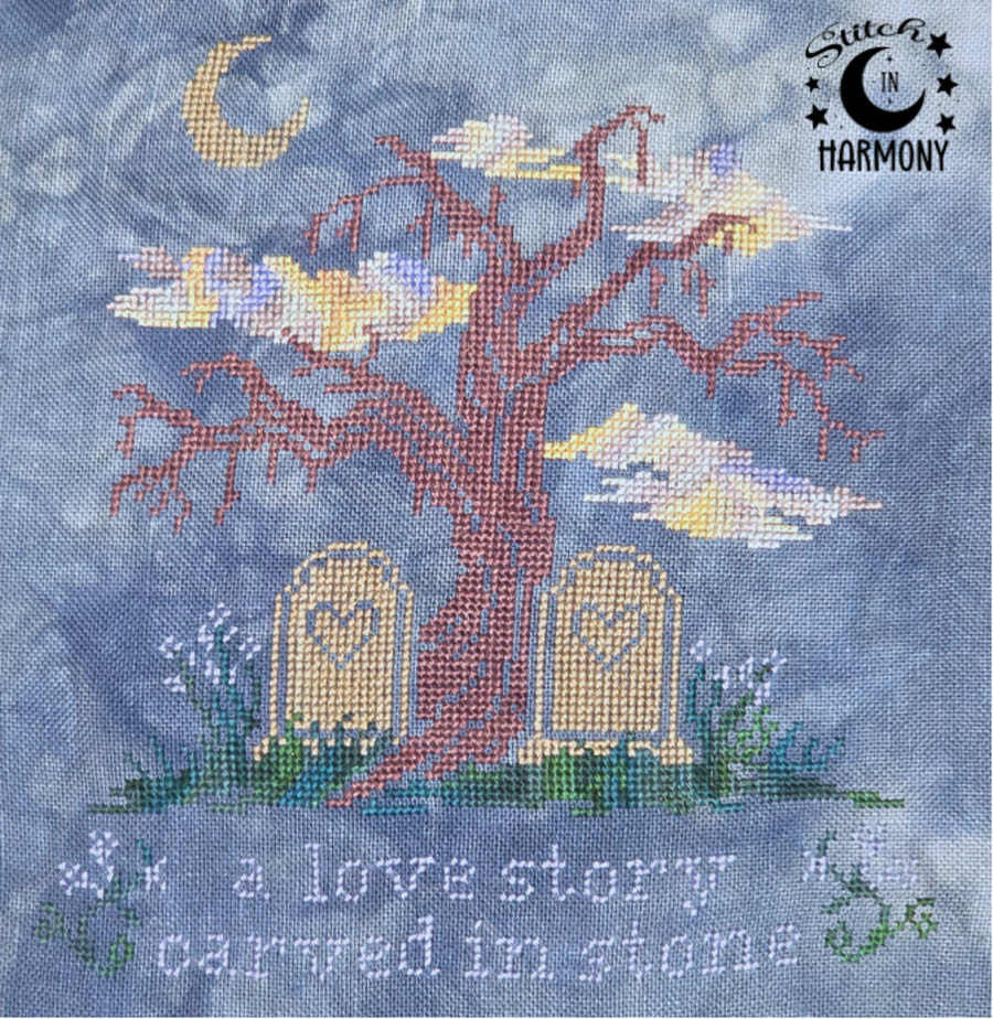 A needlepoint canvas design featuring a bare tree with a red-brown trunk, two tombstones with heart-shaped windows, a yellow crescent moon, and the text 'a love story carved in stone' on a mottled blue-gray background. The 'Sitter in Harmony' brand logo is in the top right corner.