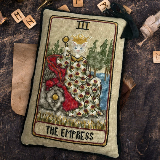 Embroidered pillow with 'The Empress' tarot card design on a wooden surface.