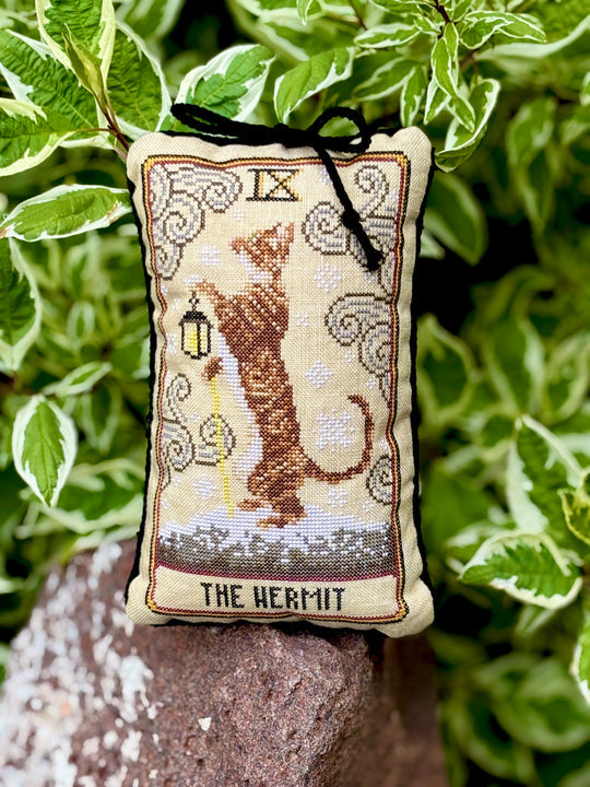 Decorative pillow with 'The Hermit' tarot card design, featuring a cat, on a natural background.