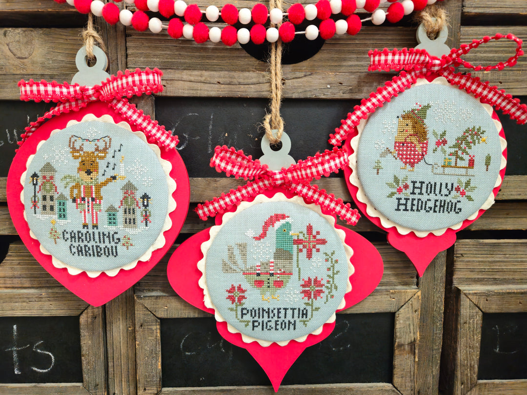 Decorative Christmas ornaments with cross-stitch designs on a wooden background