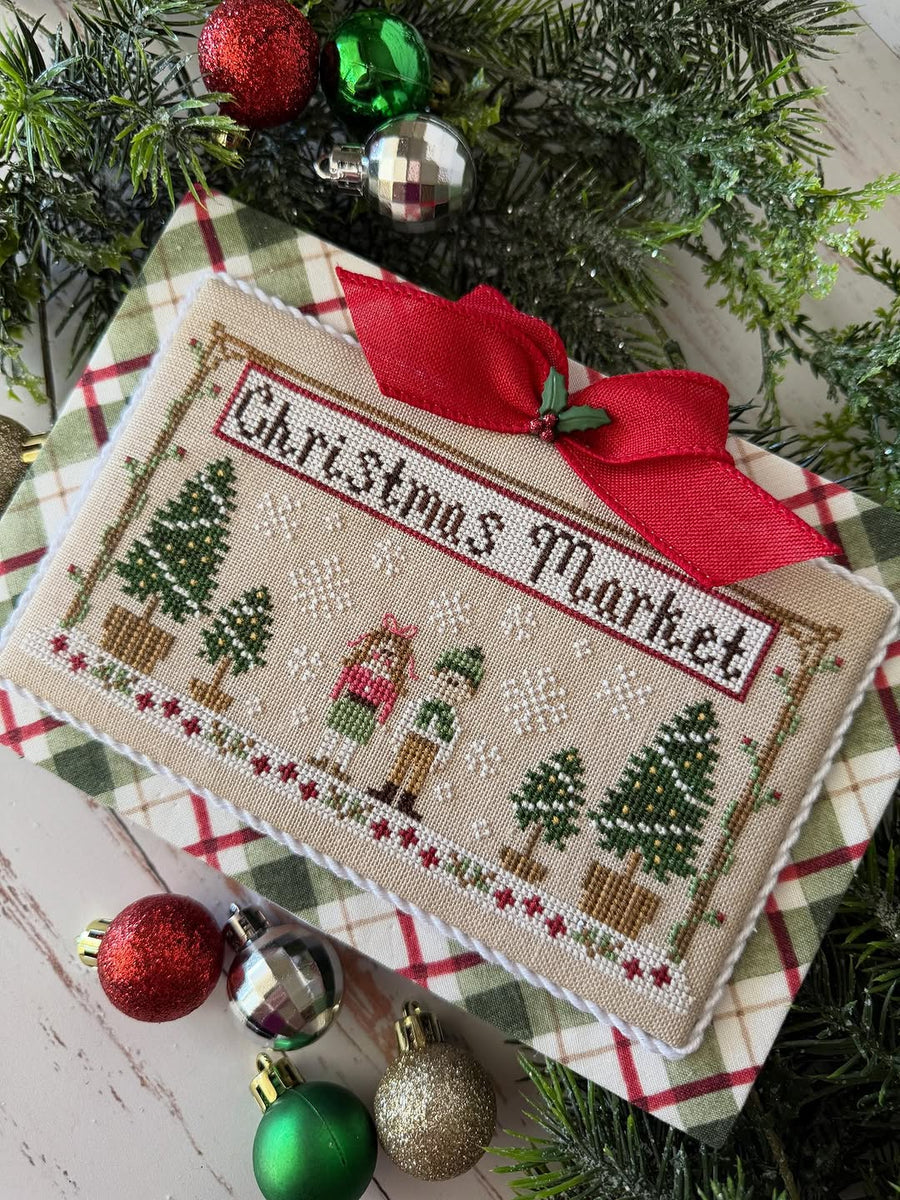 Decorative Christmas ornament with 'Christmas Market' text and festive design on a plaid fabric background.