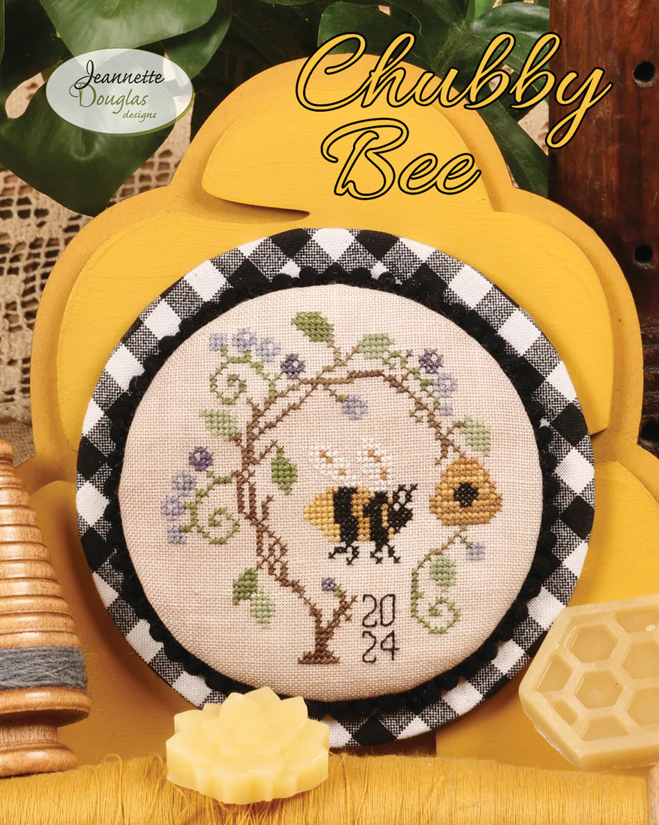 Cross-stitched bee design with floral elements on a checkered border, set against a yellow background.