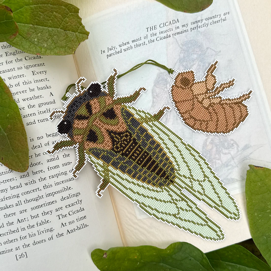 Embroidered cicada on a book with green leaves
