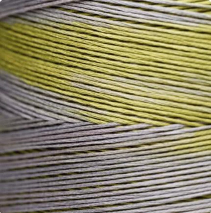 A close-up of tightly wound thread strands showing a color-shifting pattern with alternating bands of pale yellow-green and light gray.