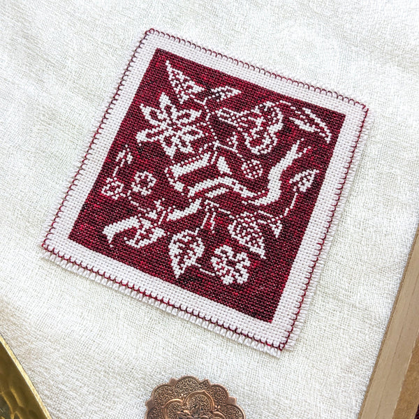 Embroidered square with floral pattern on a white fabric background