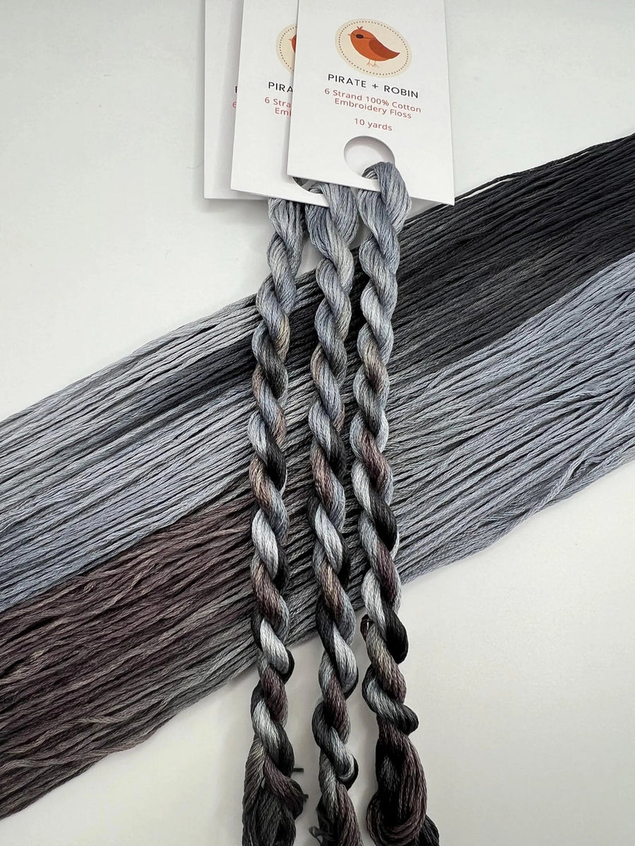 light and dark Gray thread skeins with a brand label on a light background