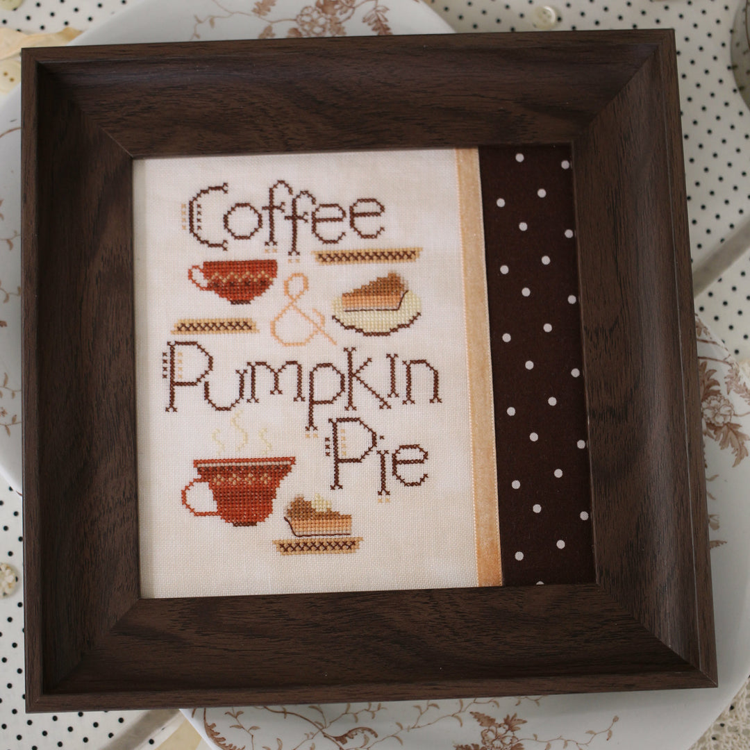 Cross-stitched piece with 'Coffee & Pumpkin Pie' text and images in a wooden frame.