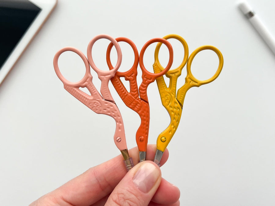three stork scissors in coral, orange and yellow held up together