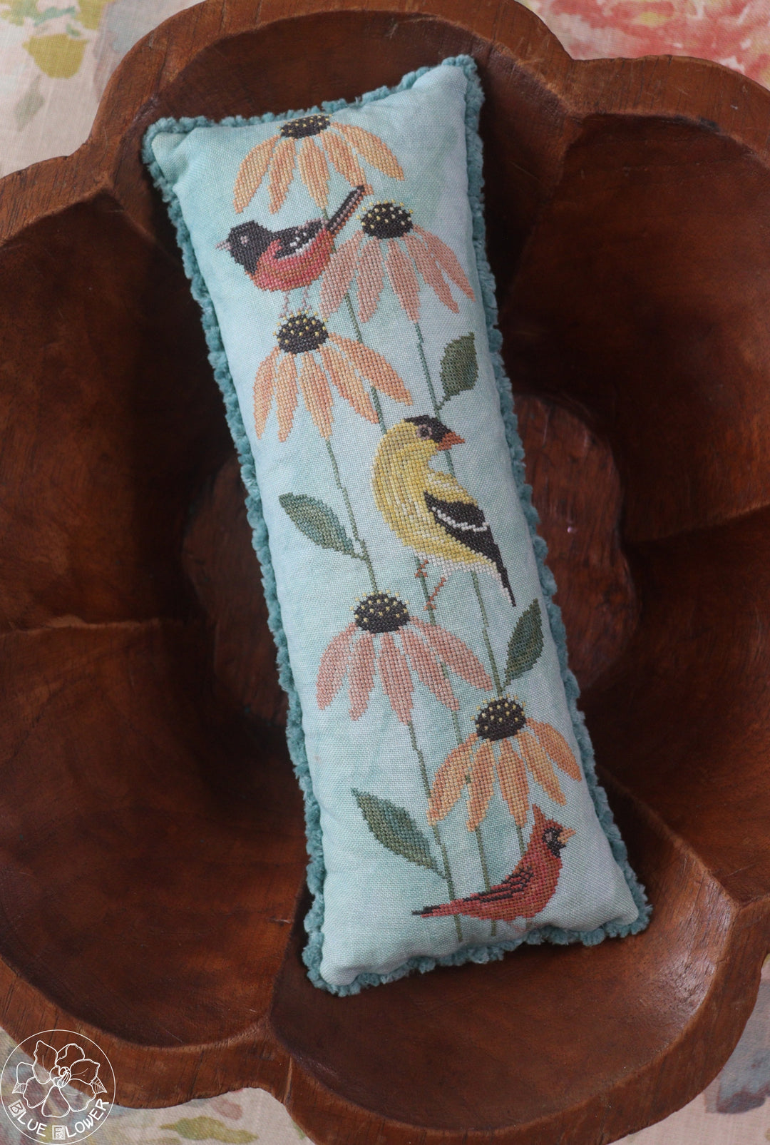 Decorative pillow with floral and bird pattern on a wooden surface