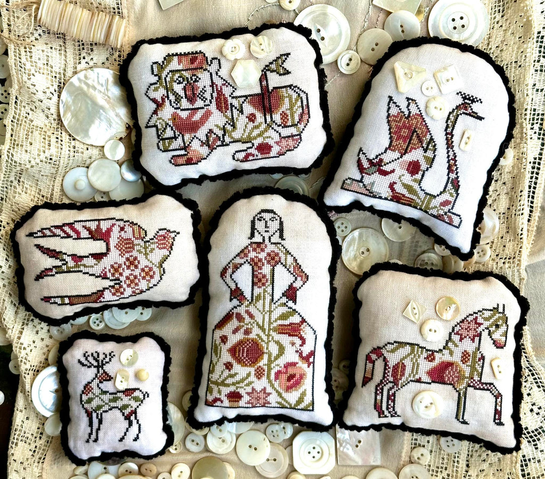 Set of embroidered pieces with floral and animal designs on a textured fabric background.