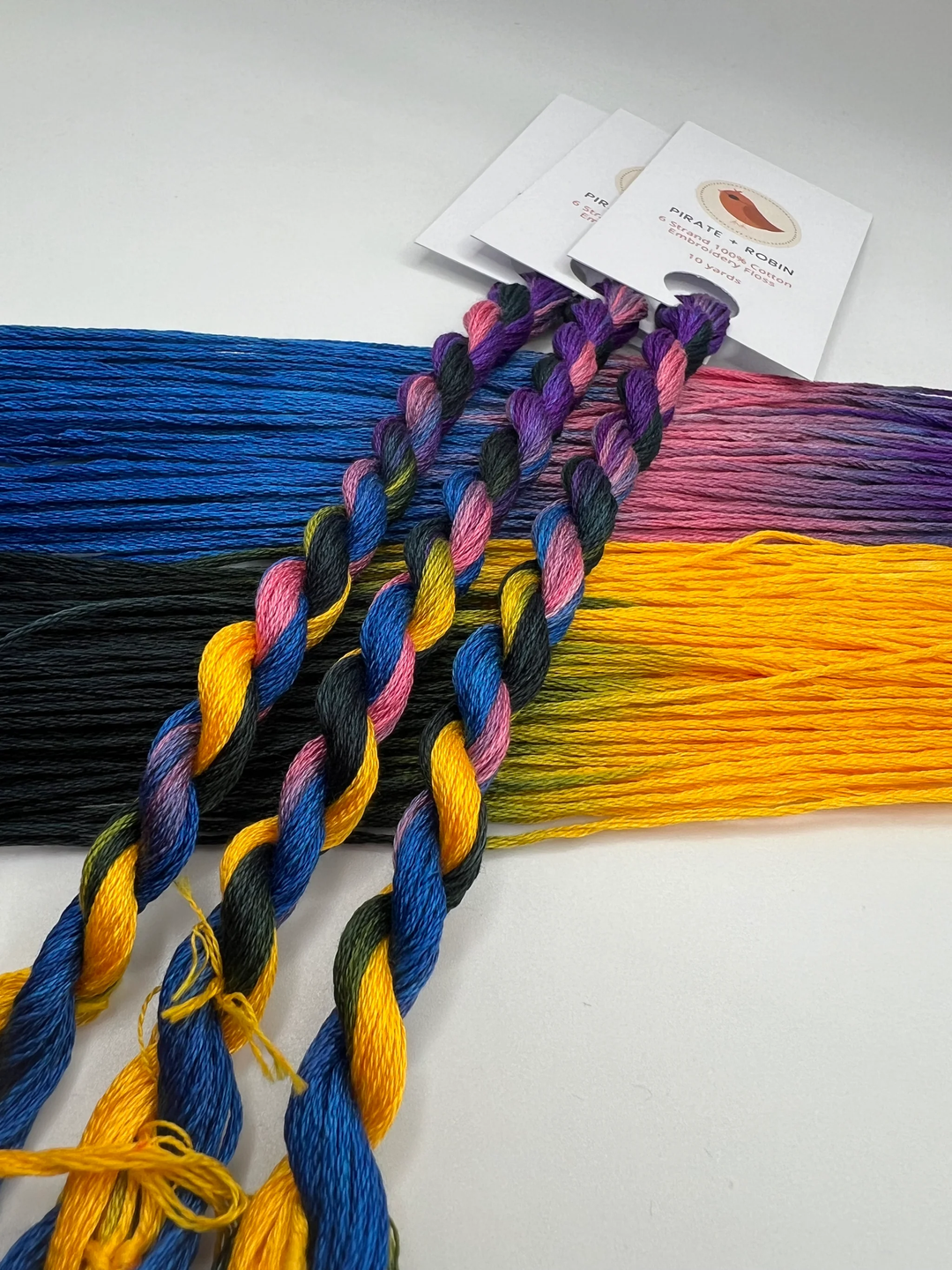 Colorful pink blue purple yellow and black embroidery floss with packaging on a white background