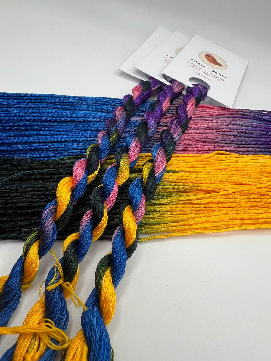 Colorful pink blue purple yellow and black embroidery floss with packaging on a white background