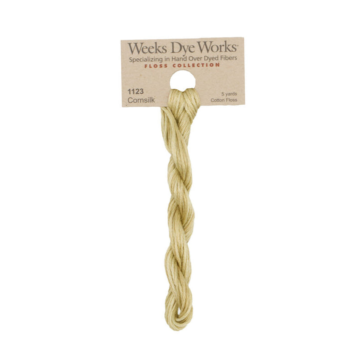 A single skein of Weeks Dye Works Corn silk cotton fiber, product number 1123, packaged on a cardboard header card against a plain white background.