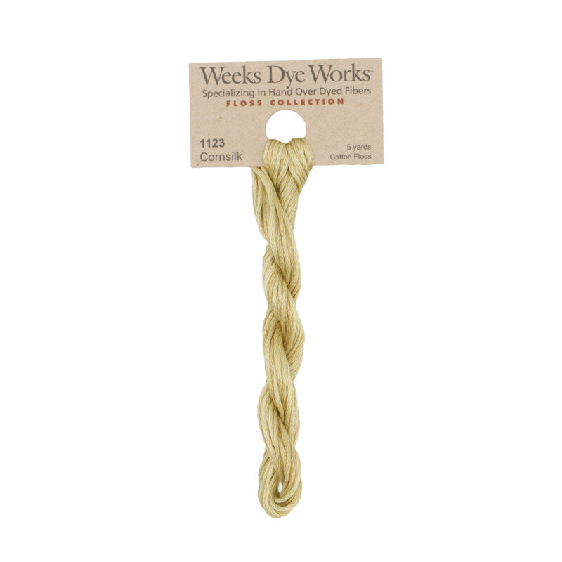 A single skein of Weeks Dye Works Corn silk cotton fiber, product number 1123, packaged on a cardboard header card against a plain white background.