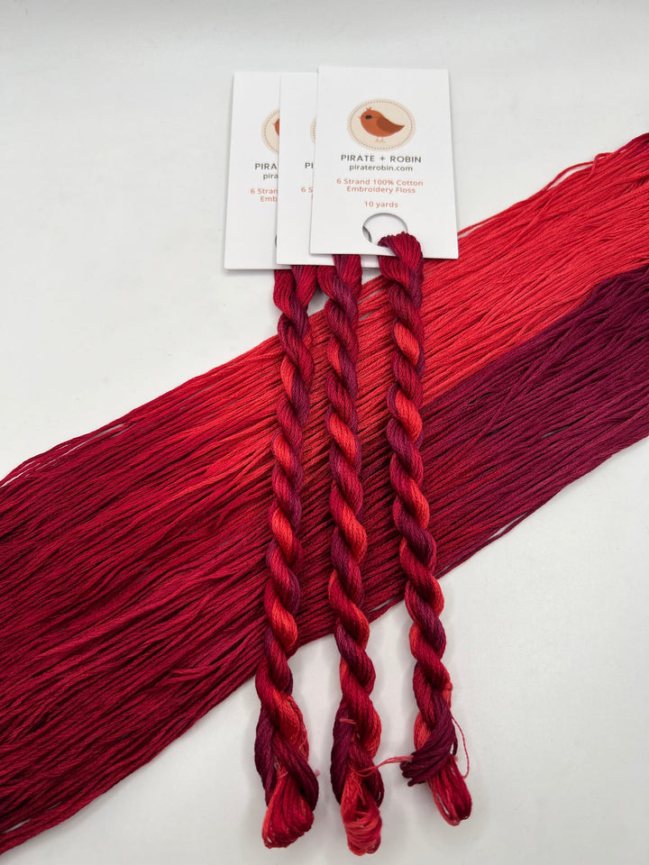 Red and pink embroidery floss with a brand label on a white background
