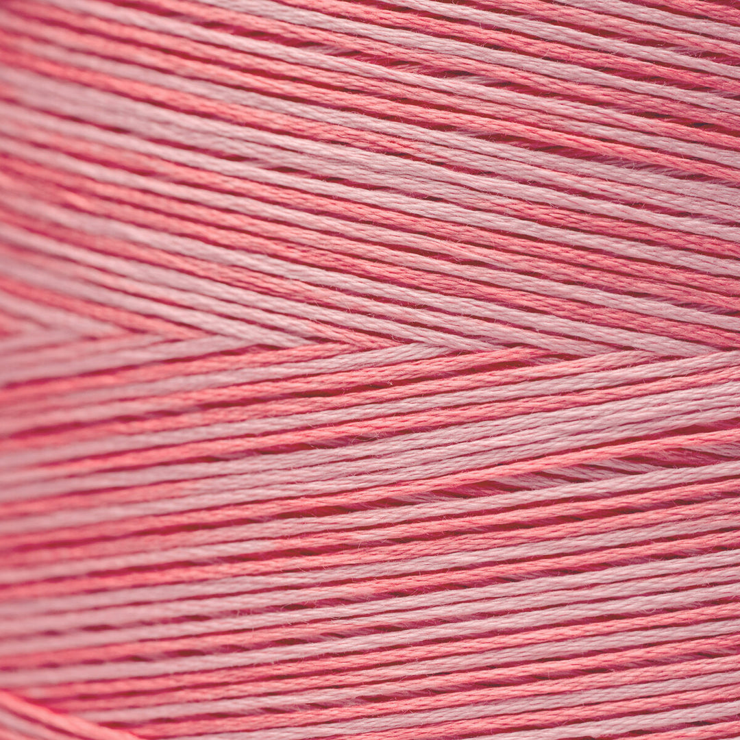 A close-up texture shot of pink and white yarn wound tightly, showing the fine strands and chevron pattern.