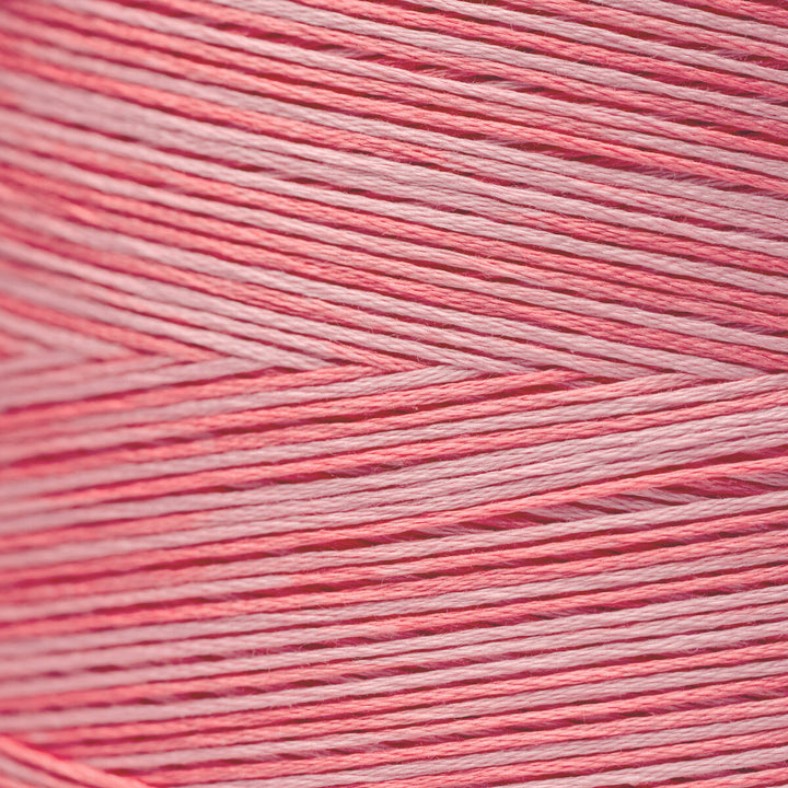 A close-up texture shot of pink and white yarn wound tightly, showing the fine strands and chevron pattern.