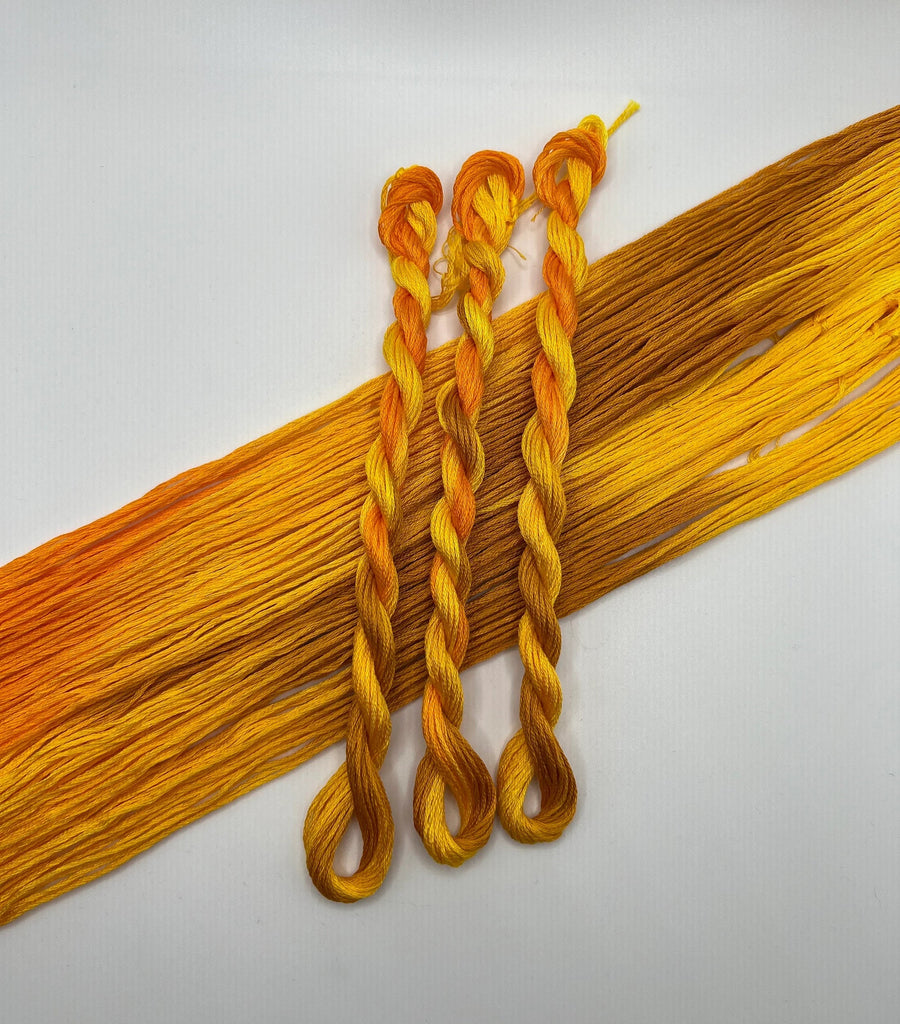 Three braided yellow floss skeins on a white background