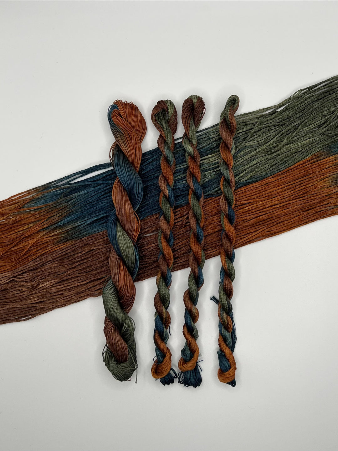 Braided floss in various grey brown navy colors on a white background