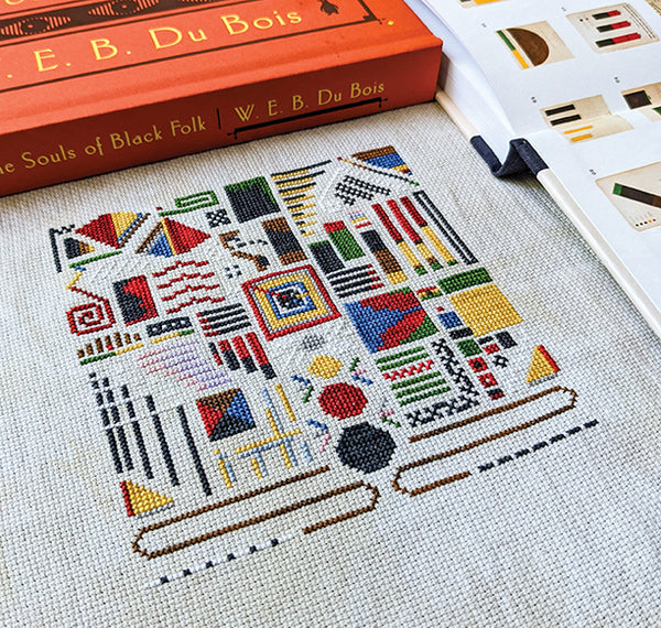Cross stitch pattern for 'Data Portraits in Paris 1900' with a book and pattern guide in the background.