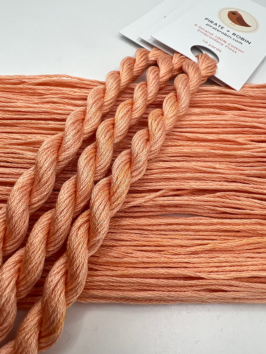 Peach-colored yarn with a packaging label on a light gray background