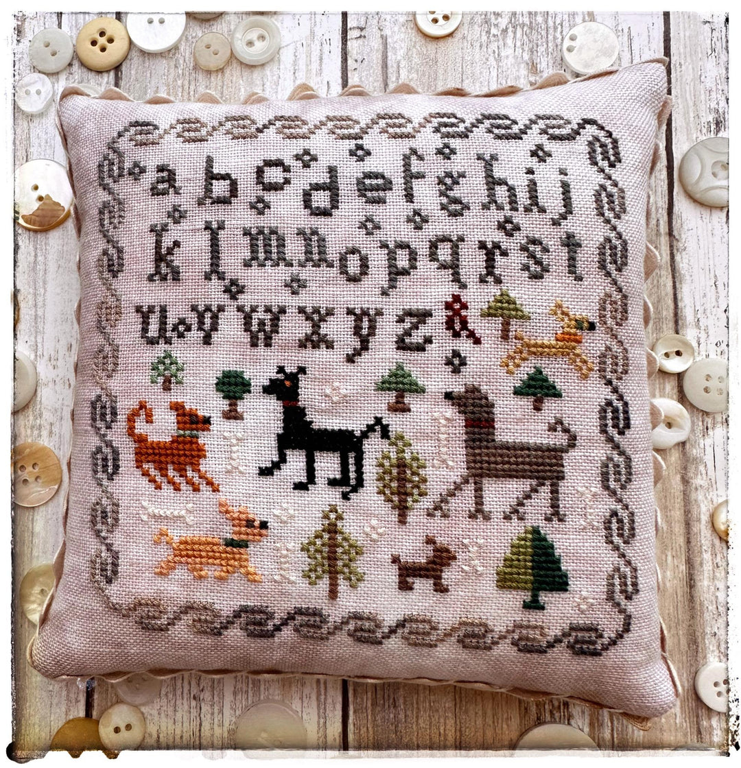 Decorative pillow with cross-stitched design featuring animals and trees on a wooden background.