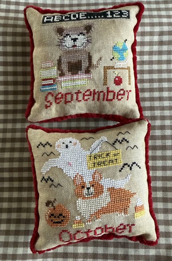 Two cross-stitched pillows with animal-themed designs on a checkered fabric background.
