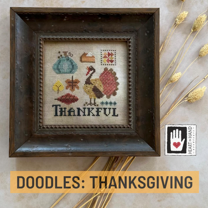 Framed cross-stitched piece with a turkey and 'Thankful' text, surrounded by autumnal elements.