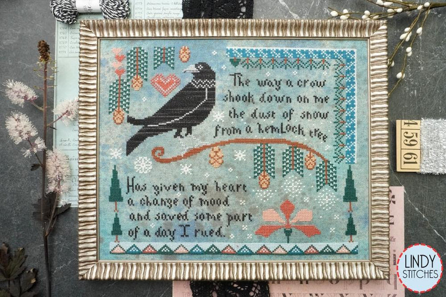 Framed cross-stitched artwork with a crow and nature elements on a textured surface.