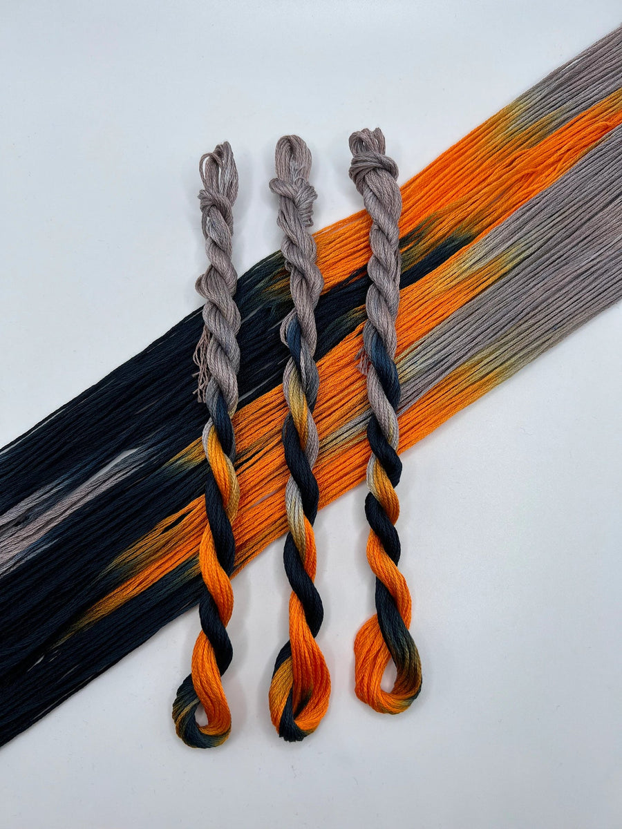 Three braided thread skeins in black, orange, and gray on a white background.