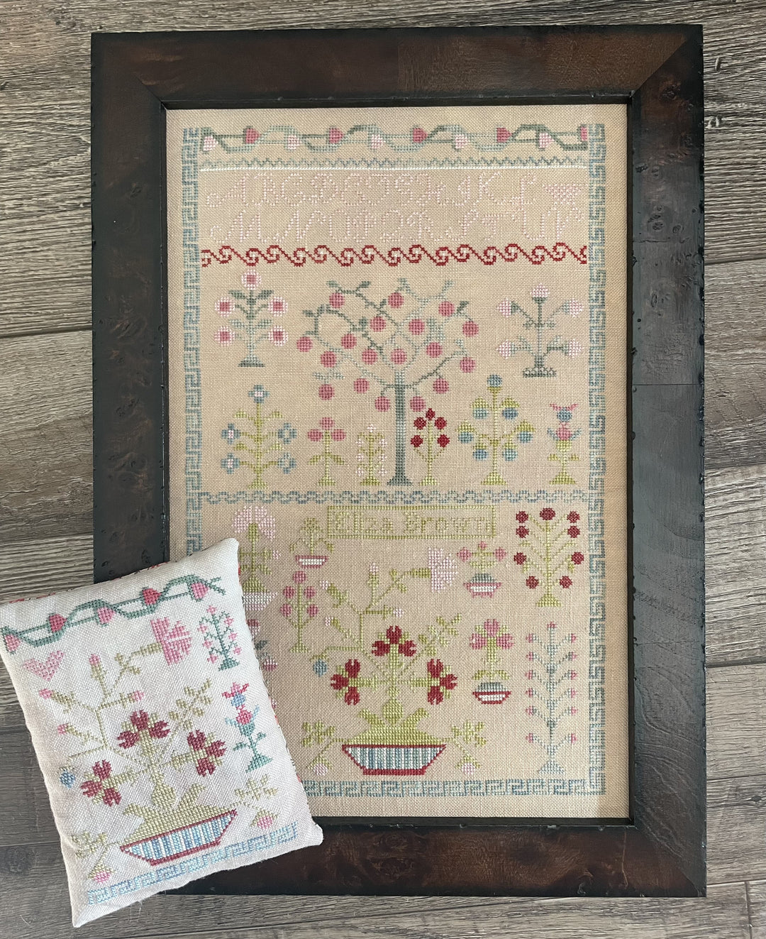 Framed cross-stitched pattern on fabric with a wooden frame on a wooden surface