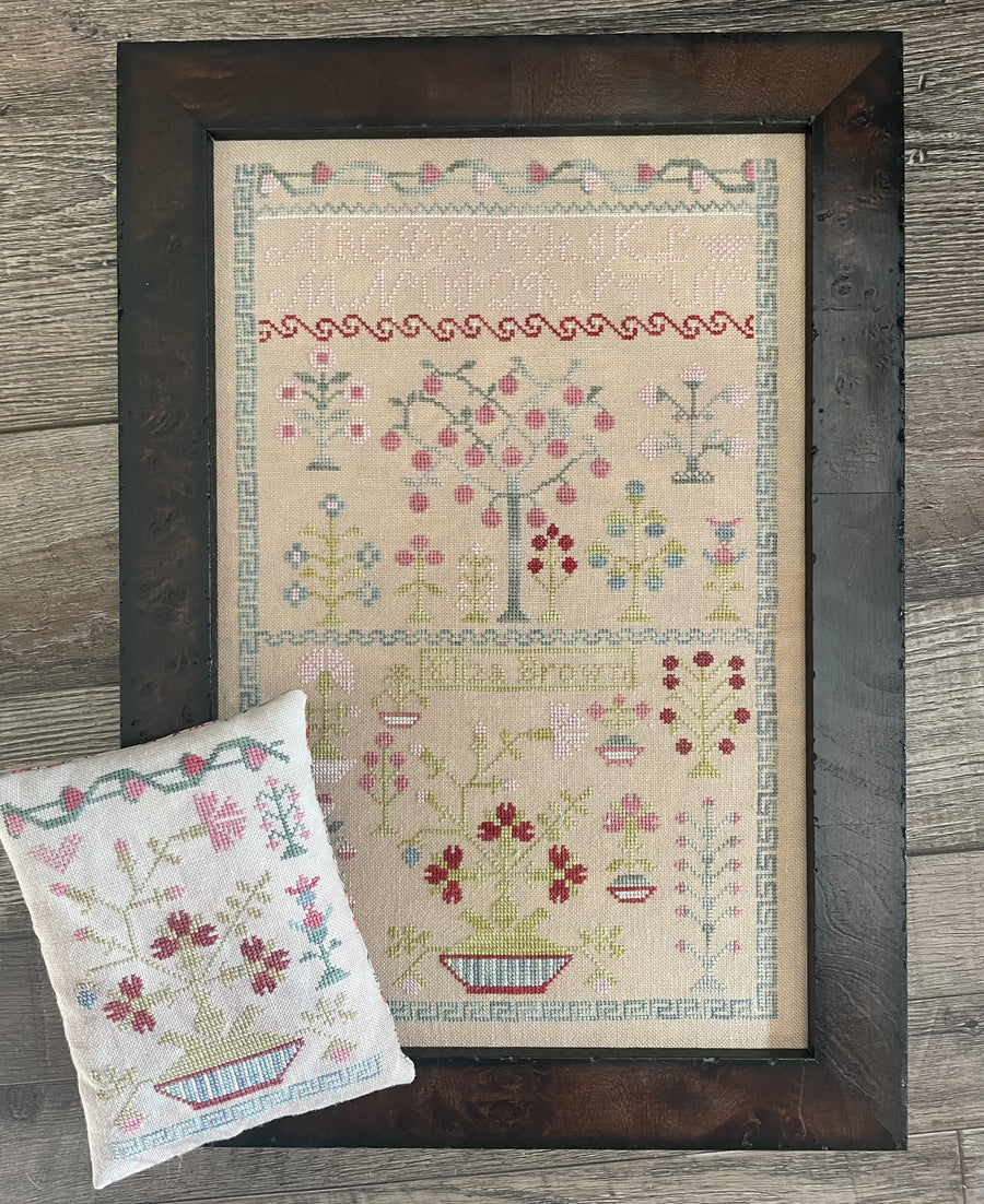 Framed cross-stitched pattern on fabric with a wooden frame on a wooden surface