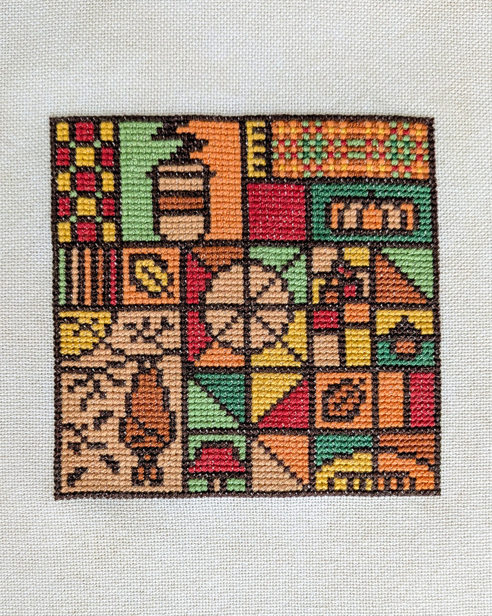 A square cross-stitch or needlepoint artwork on a white fabric background, featuring a colorful patchwork design with geometric blocks and stylized motifs in orange, green, red, yellow, beige, and brown.