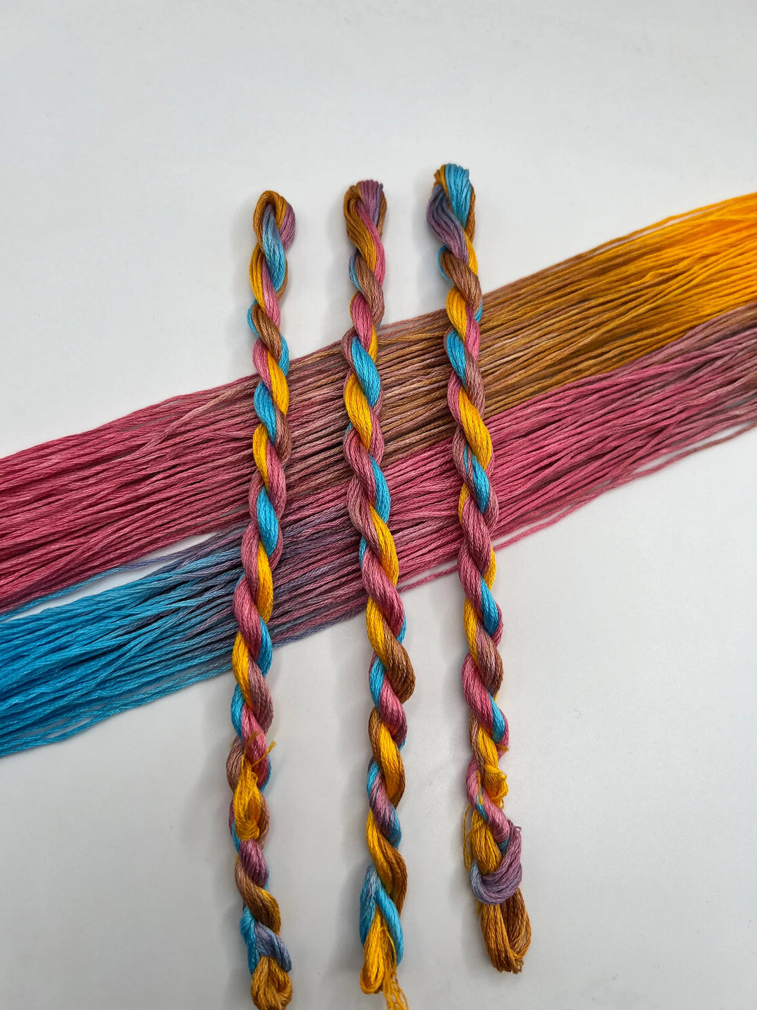 Colorful thread skeins of yellow pink and blue floss on a white background