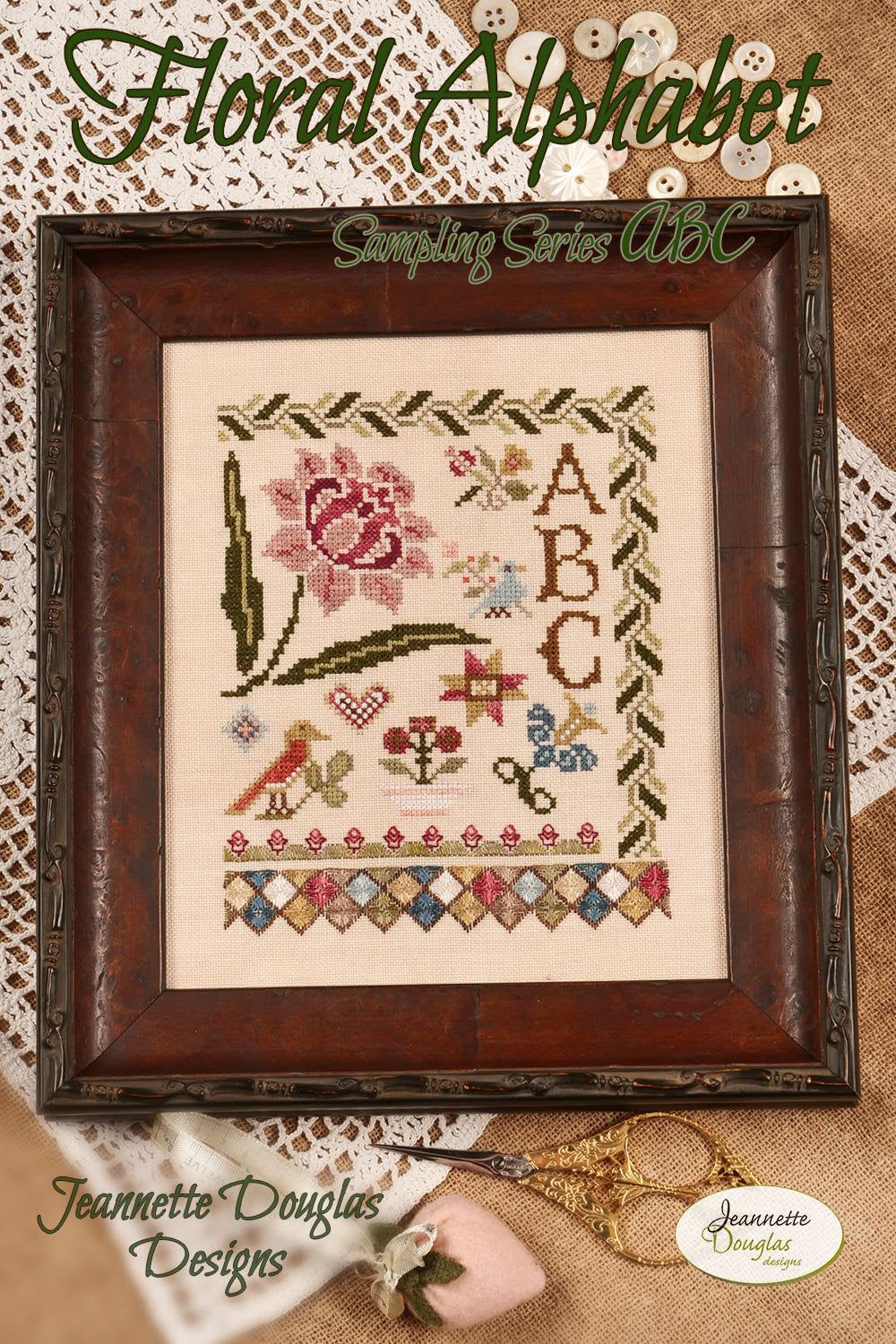 Floral Alphabet cross-stitch pattern with wooden frame on textured fabric background