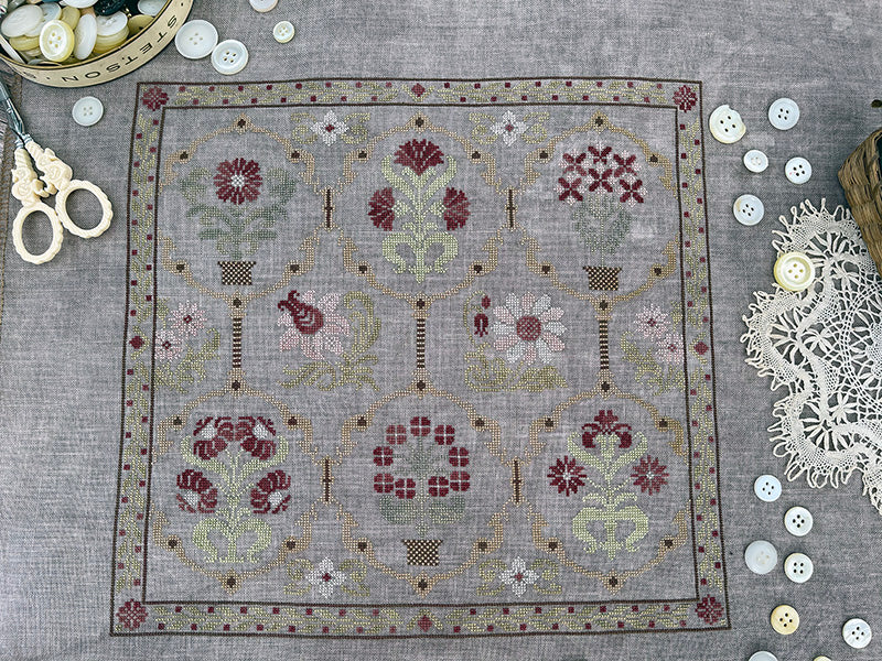 Embroidery pattern on fabric with sewing tools and buttons on a gray surface