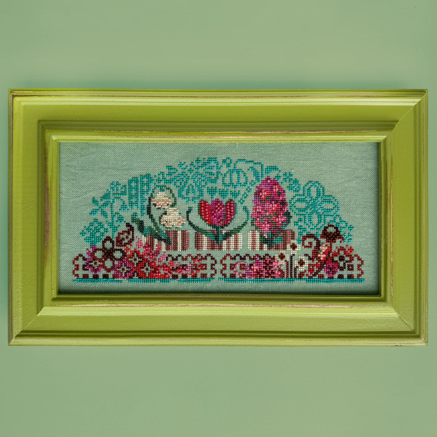 Framed cross-stitched artwork with floral design on a green background