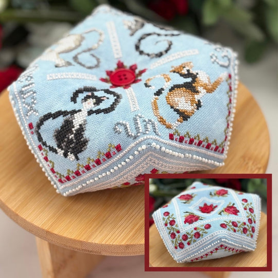 Hexagonal embroidered fabric with dog and rose design on a wooden stool.
