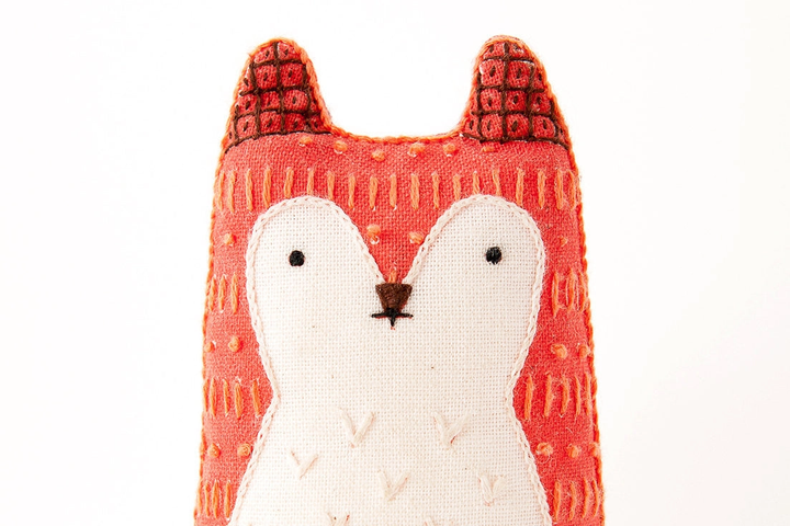 Stuffed fox toy with red patterned fur on a white background