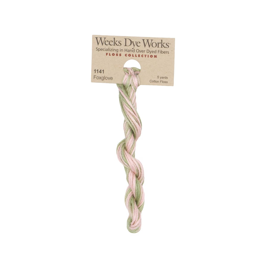 A twisted bundle of Weeks Dye Works Floss Collection cotton thread in the shade Foxglove, featuring soft pastel pink and sage green threads on a kraft paper hanger.