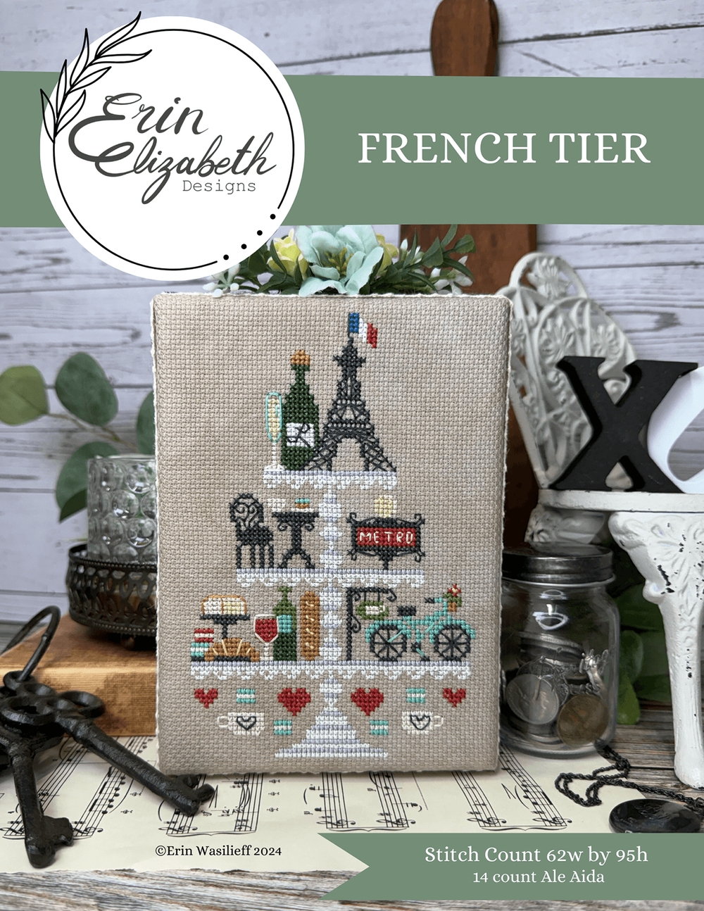 Cross-stitched design of a French-themed tiered cake with 'Erin Elizabeth Designs' branding.