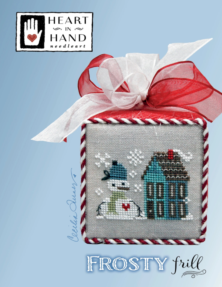 Cross-stitched design of a house and dog with a red ribbon on a blue background, featuring 'Heart in Hand Needleart'.