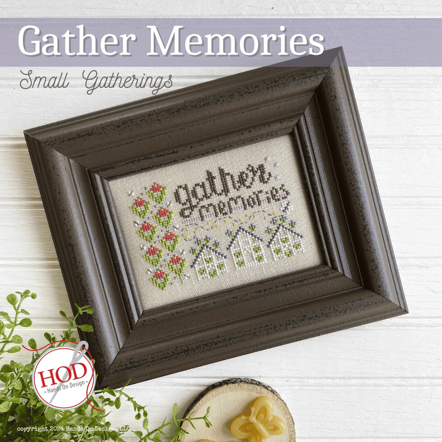 Framed cross-stitched piece with 'gather memories' text on a white background