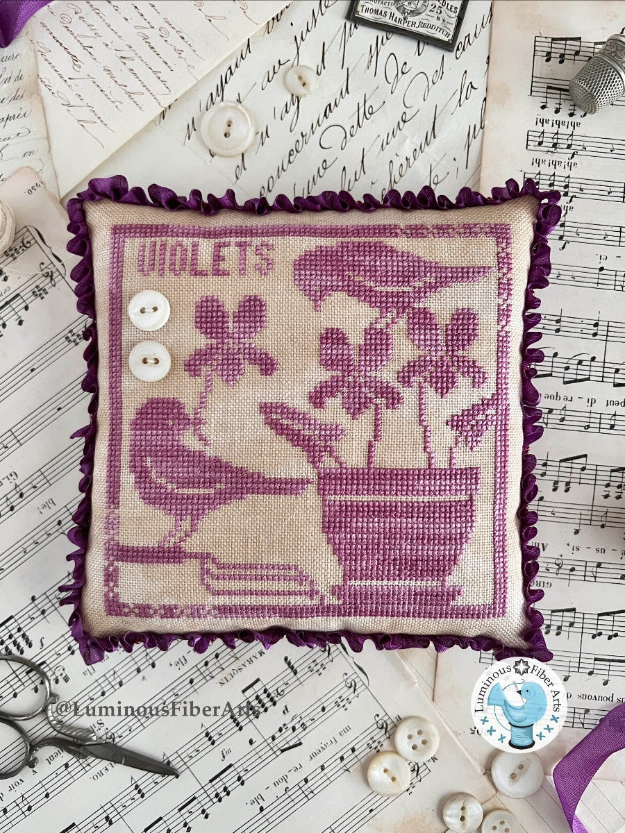 Decorative pillow with floral design and 'Violets' text on a sheet music background