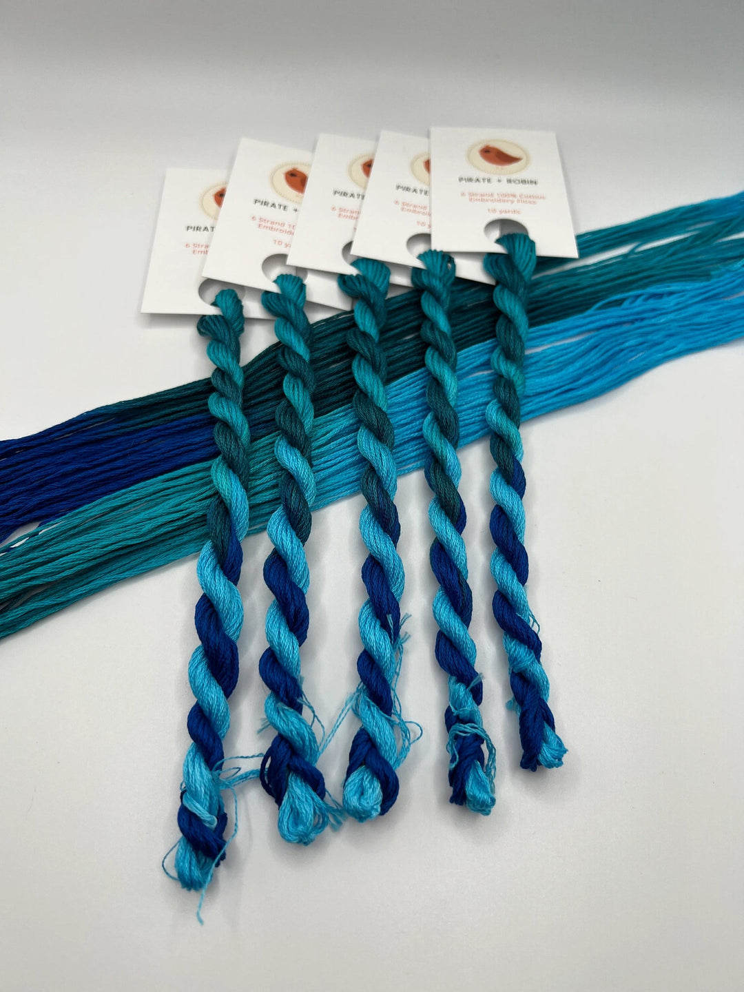 Set of blue braided yarn samples with tags on a white background