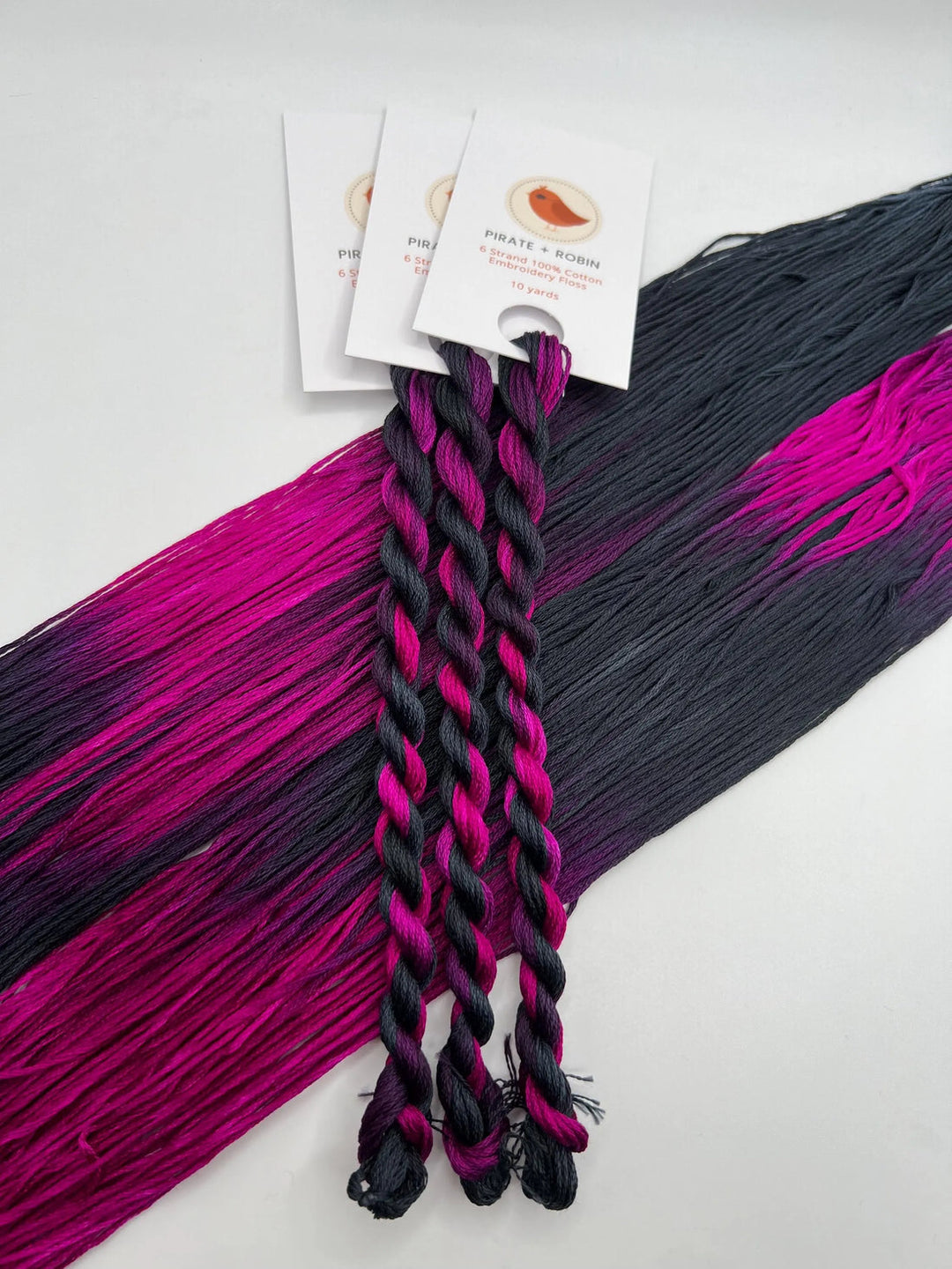 Braided thread skeins with pink and black color gradient on a white background