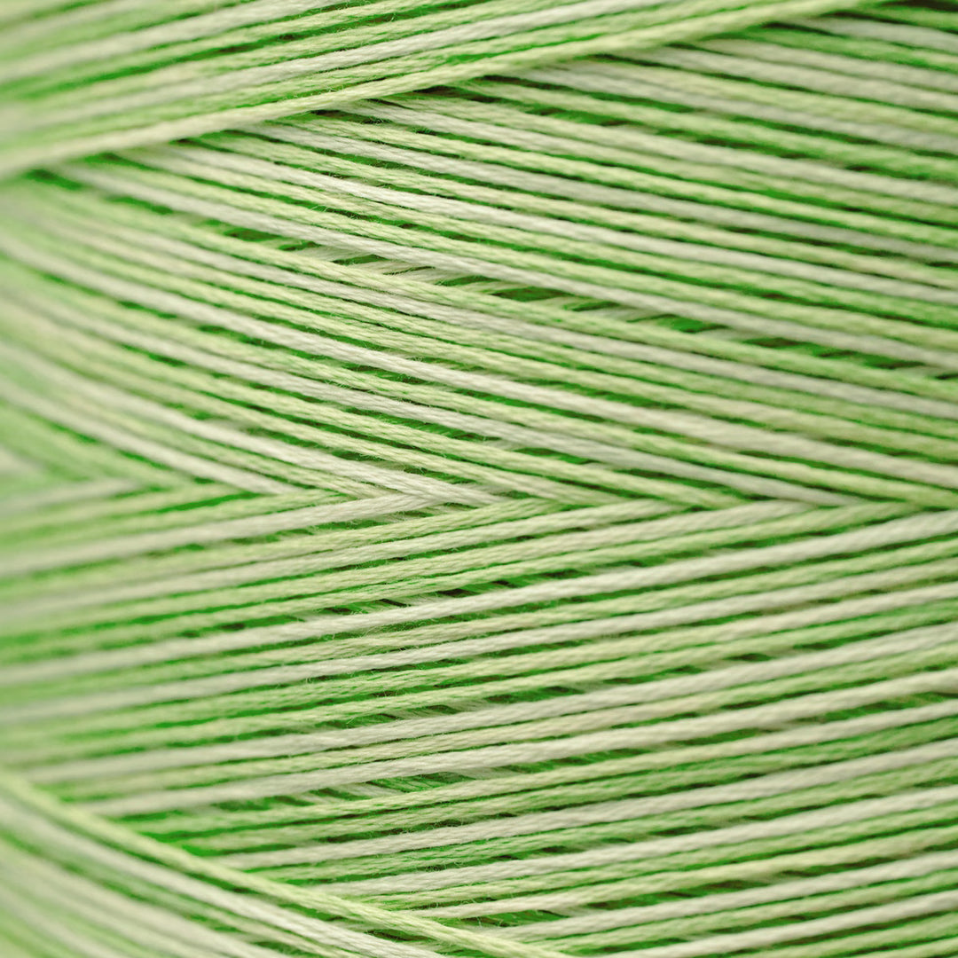 A close-up of light green and off-white yarn wound in a herringbone pattern, filling the entire frame.