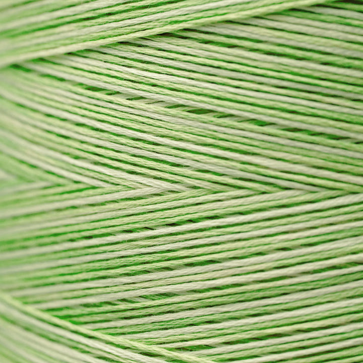 A close-up of light green and off-white yarn wound in a herringbone pattern, filling the entire frame.