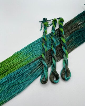 Set of braided yarn strands in green and blue on a white background