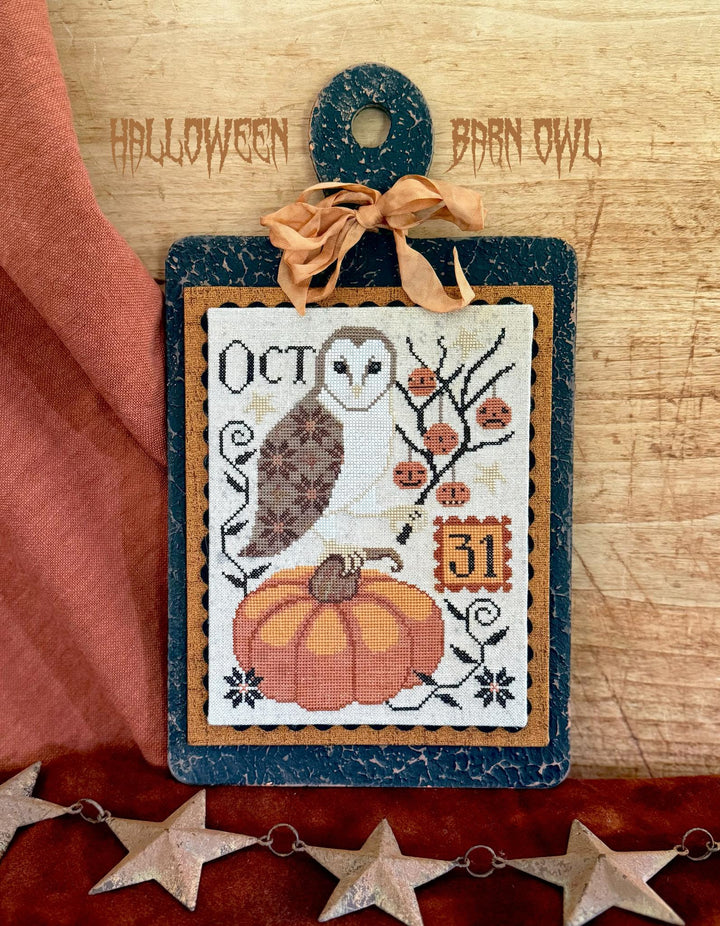 Halloween-themed cross-stitch design with an owl and pumpkin on a wooden background.